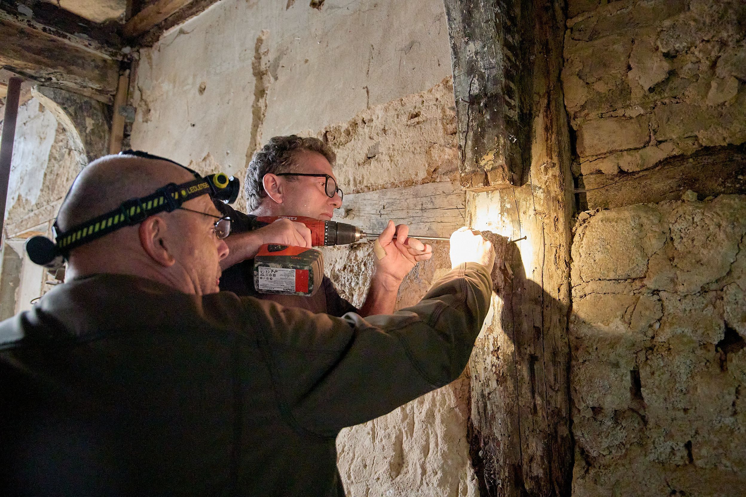 Zwei Männer arbeiten mit einem Holzbohrer in einem alten Haus in Schleiden, um Bohrkerne zu gewinnen.