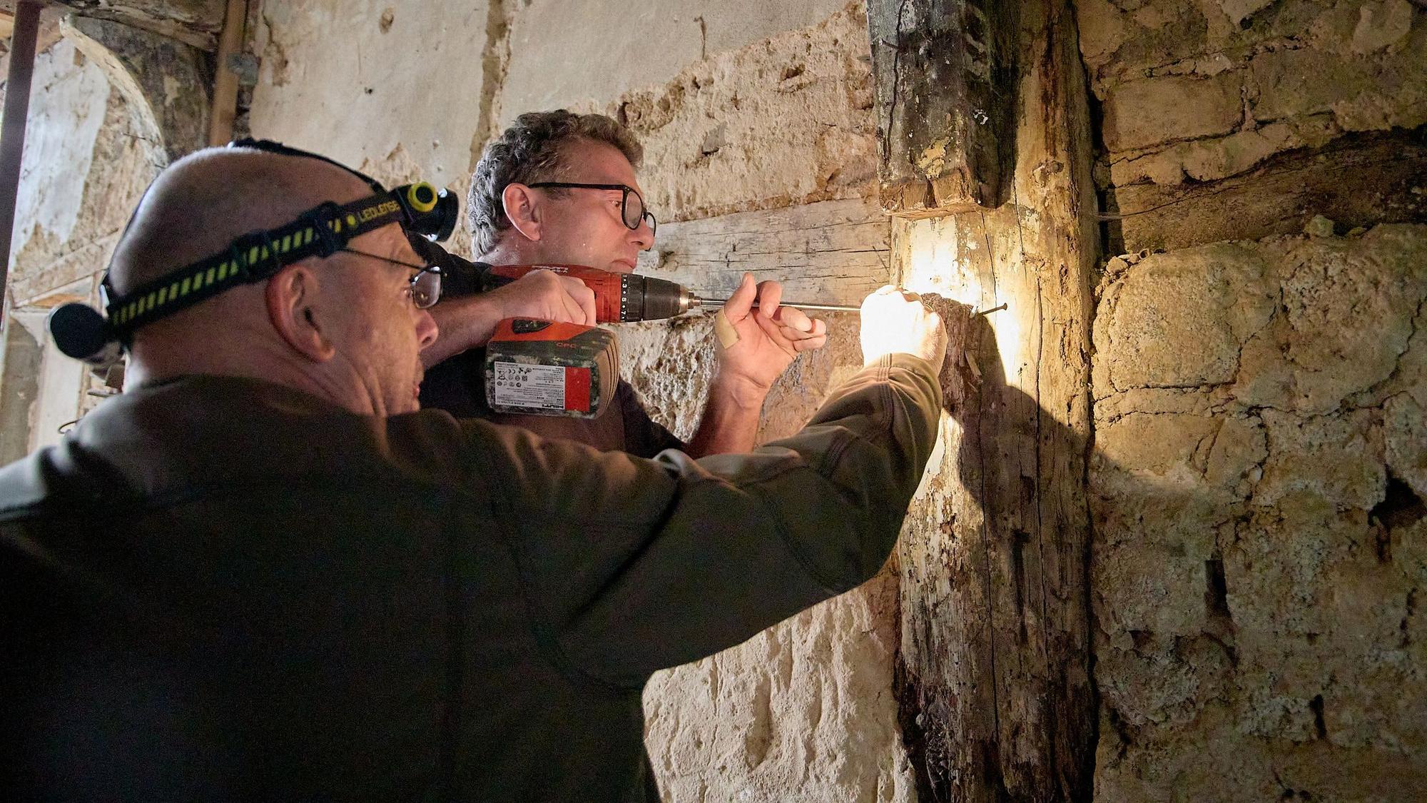 Zwei Männer arbeiten mit einem Holzbohrer in einem alten Haus in Schleiden, um Bohrkerne zu gewinnen.