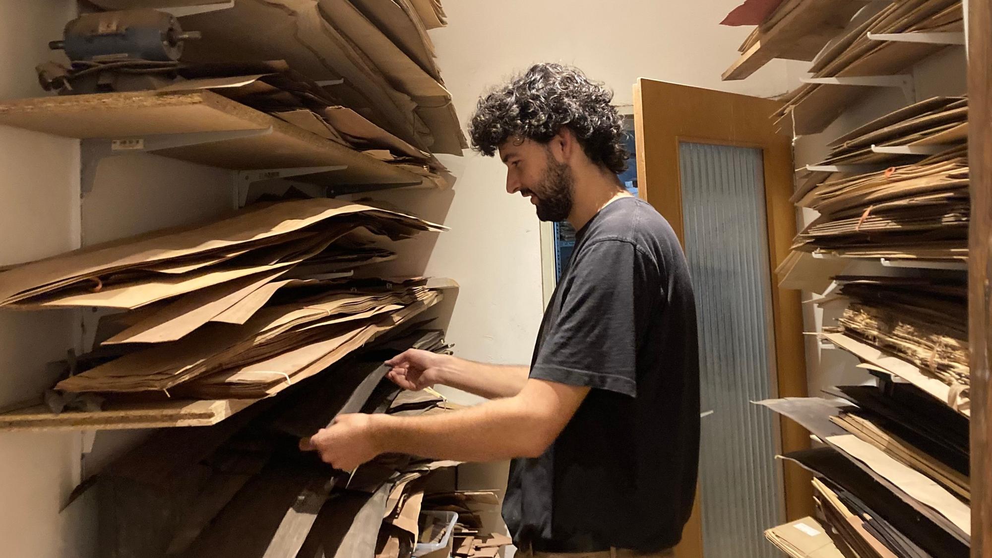 Ein Mann begutachtet Regale voller Materialien für die Gestaltung einer Gitarre.