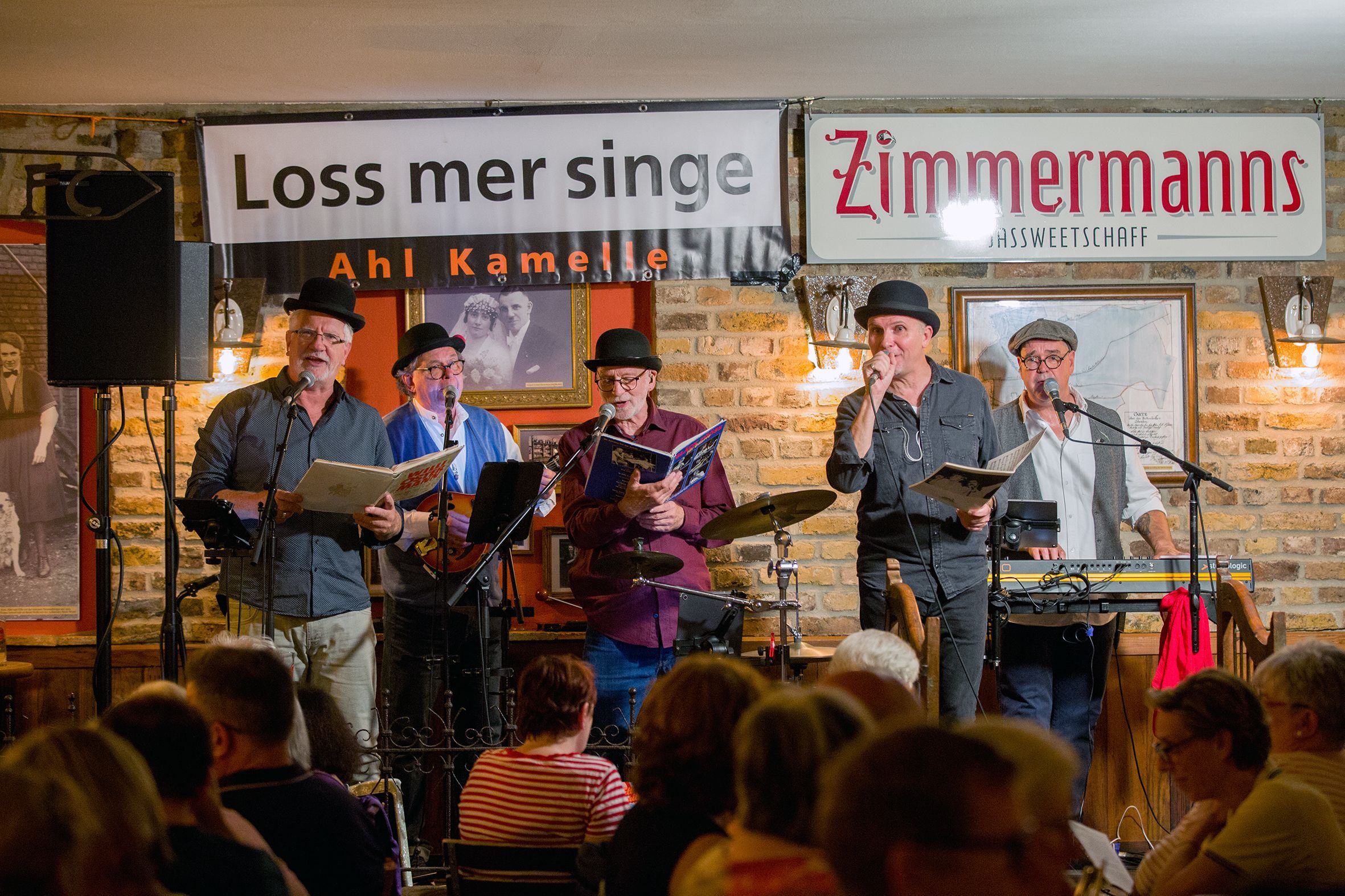 Eine fünfköpfige Band steht auf der Bühne einer Kneipe.