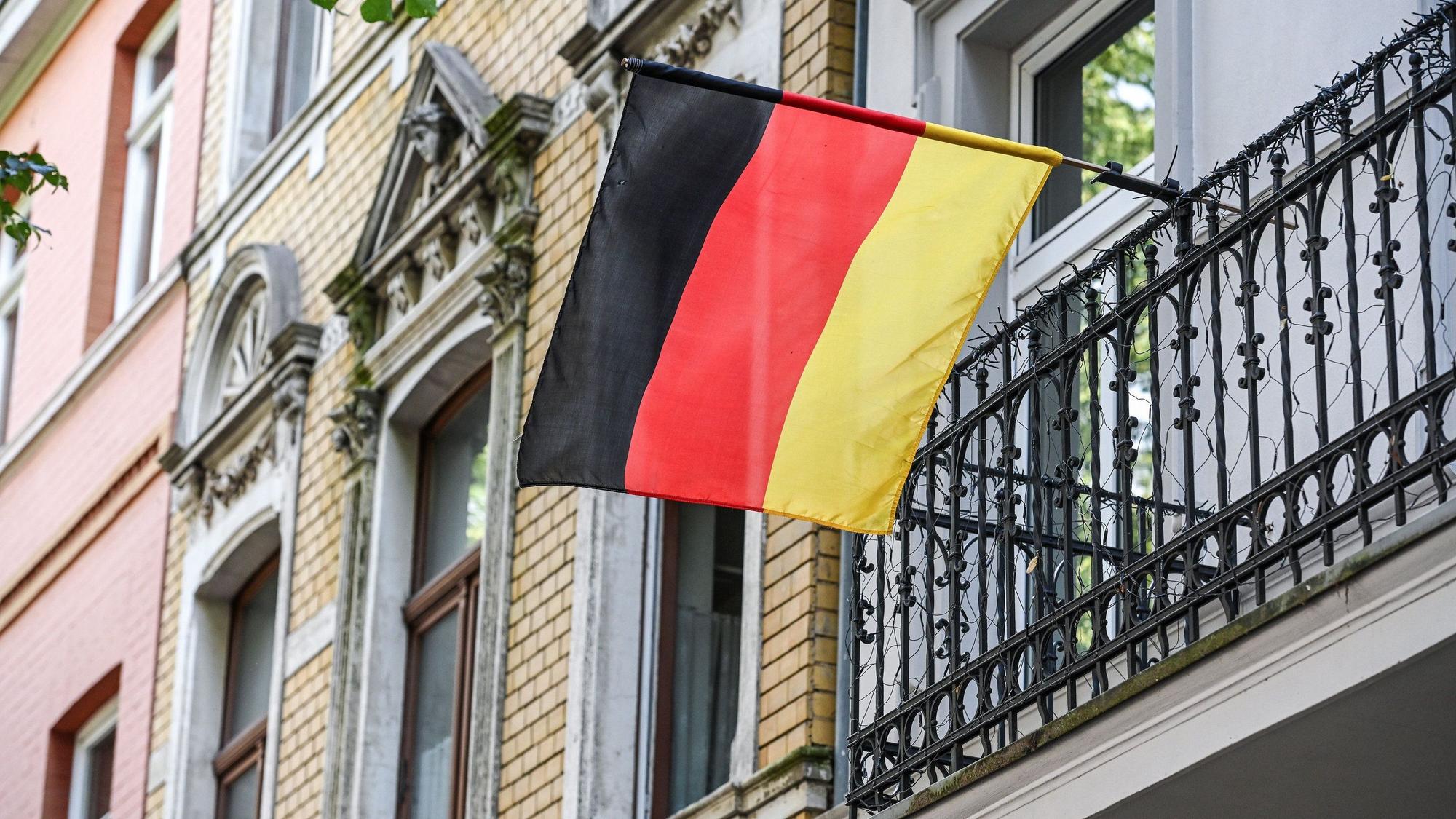 Eine Deutschlandflagge weht am Balkon eines Hauses in Bonn.