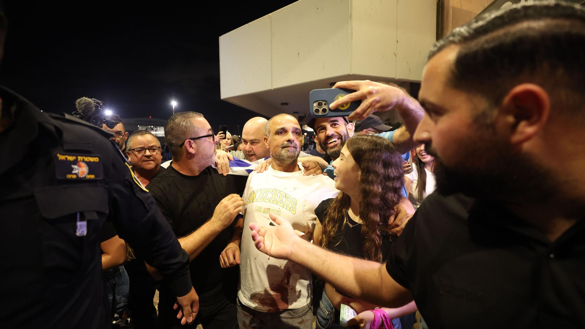 Yaniv Hayun (M), einer der Männer, die dazu beigetragen haben, den Angreifer in dem FlyDubai-Flugzeug auf dem Weg von den Vereinigten Arabischen Emiraten nach Israel außer Gefecht zu setzen, wird nach seiner Ankunft am Ben-Gurion-Flughafen begrüßt.