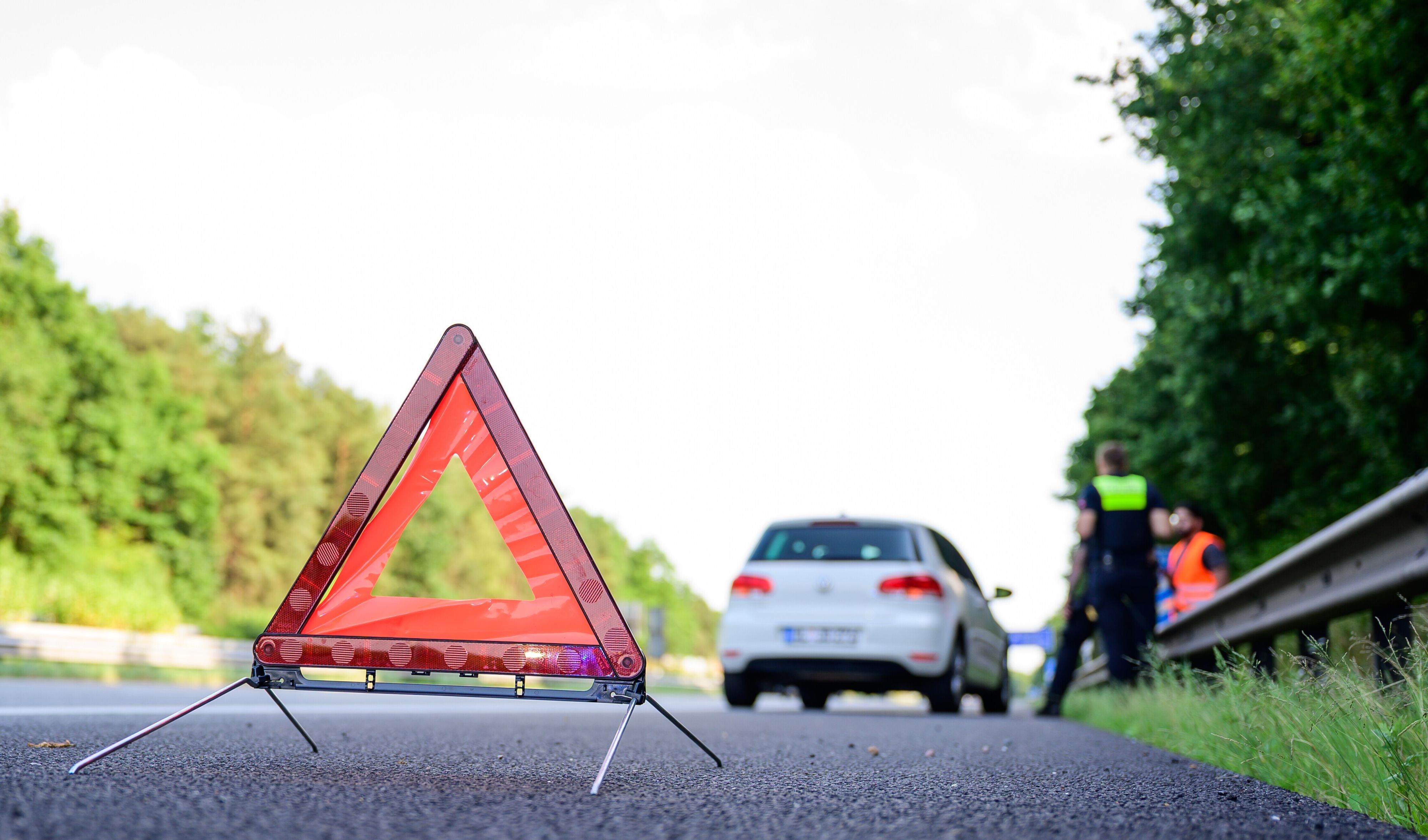 Ein Polizist nimmt einen Unfall auf einer Landstraße auf (Symbolfoto).