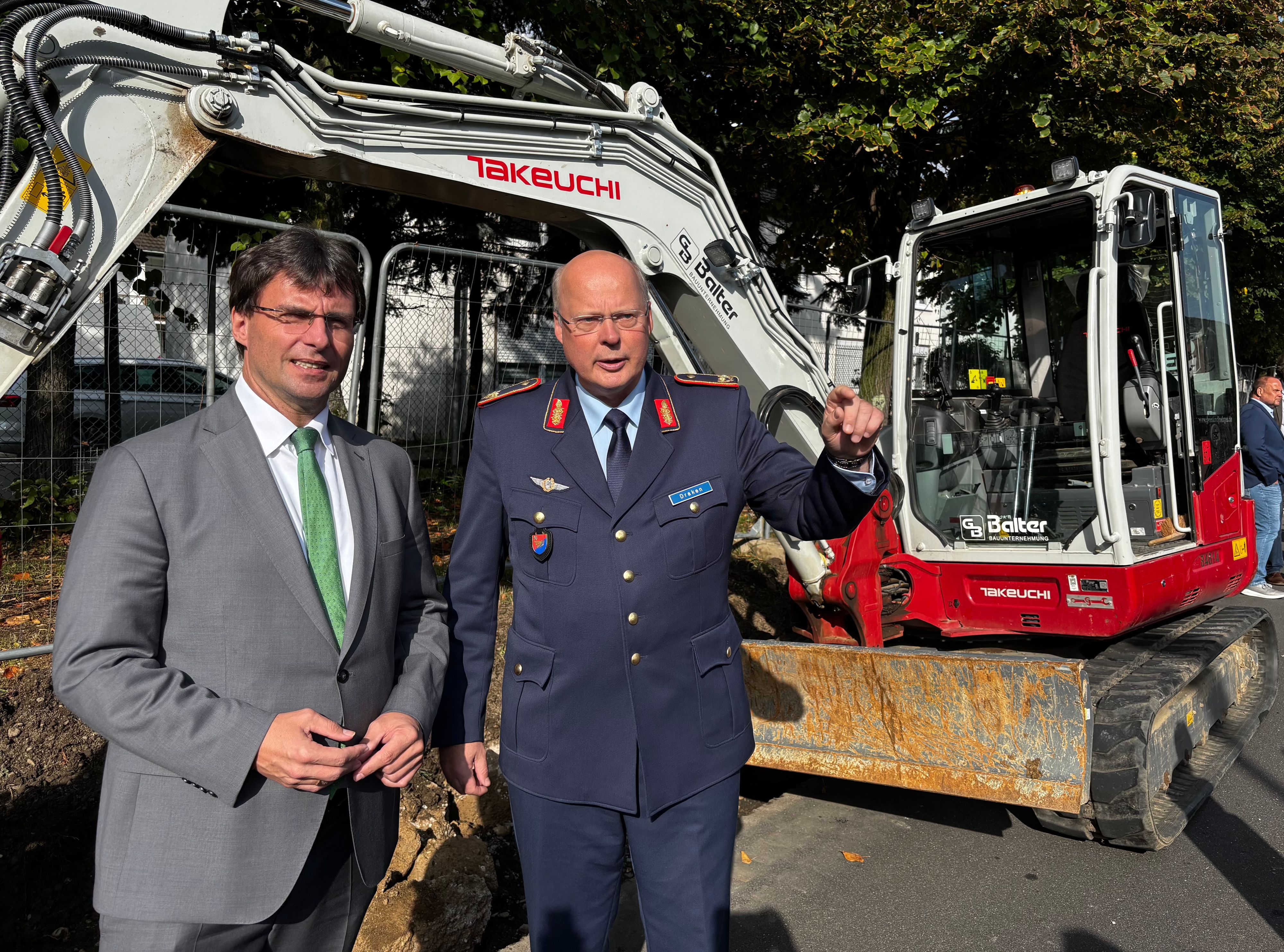 NRW-Finanzminister Marcus Optendrenk (CDU) mit Brigadegeneral Daniel Draken, Standortältester der Bundeswehr in Köln, an der Zaun-Baustelle am Luftwaffenstützpunkt Köln-Wahn.