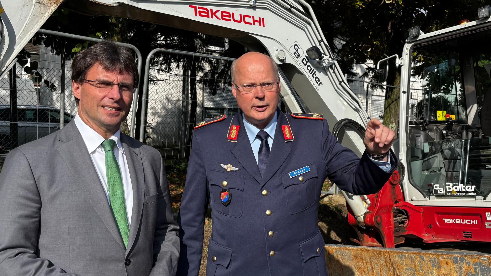 NRW-Finanzminister Marcus Optendrenk (CDU) mit Brigadegeneral Daniel Draken, Standortältester der Bundeswehr in Köln, an der Zaun-Baustelle am Luftwaffenstützpunkt Köln-Wahn.