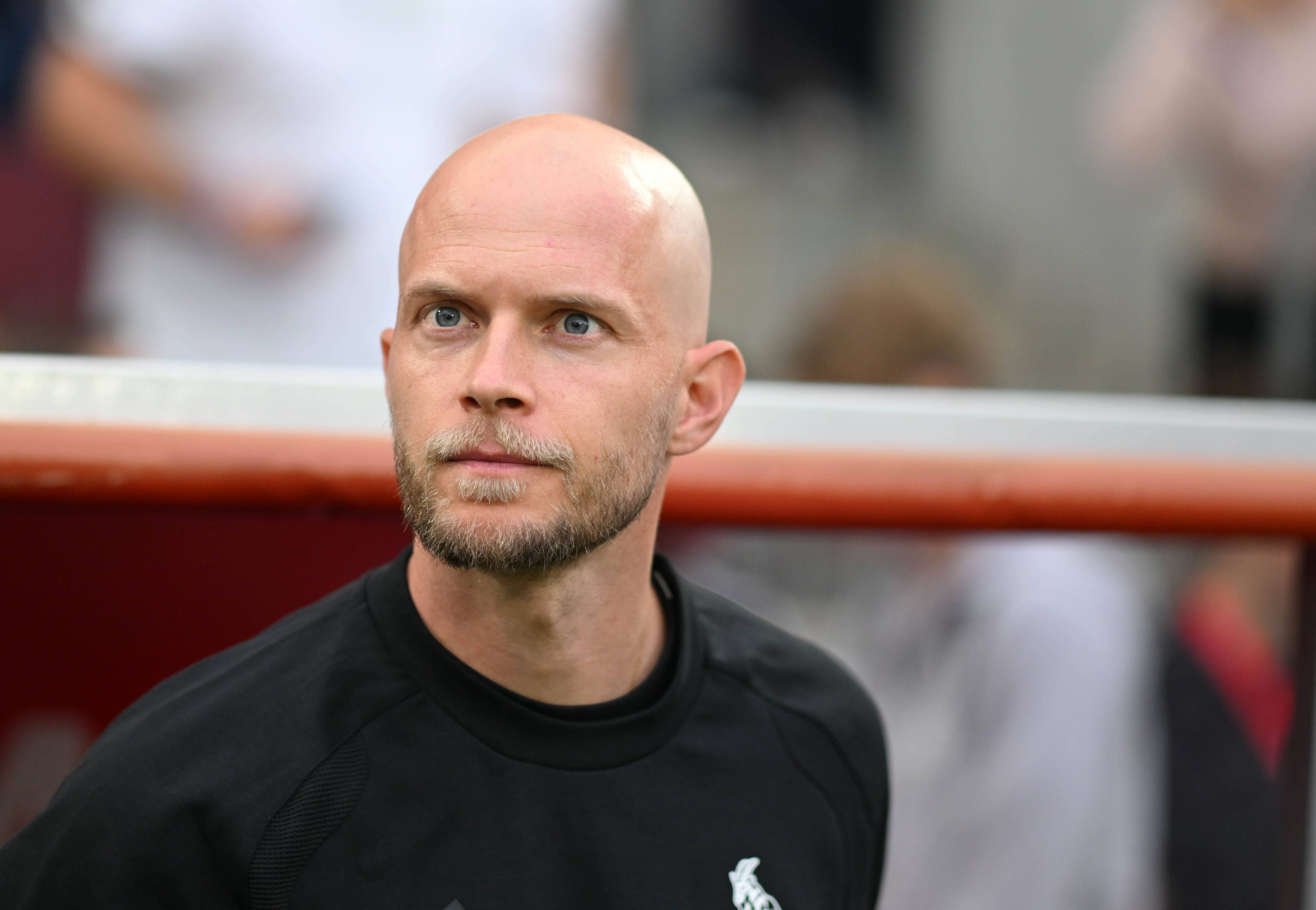 René Wagner steht vor der Trainerbank und schaut Richtung Südtribüne.
