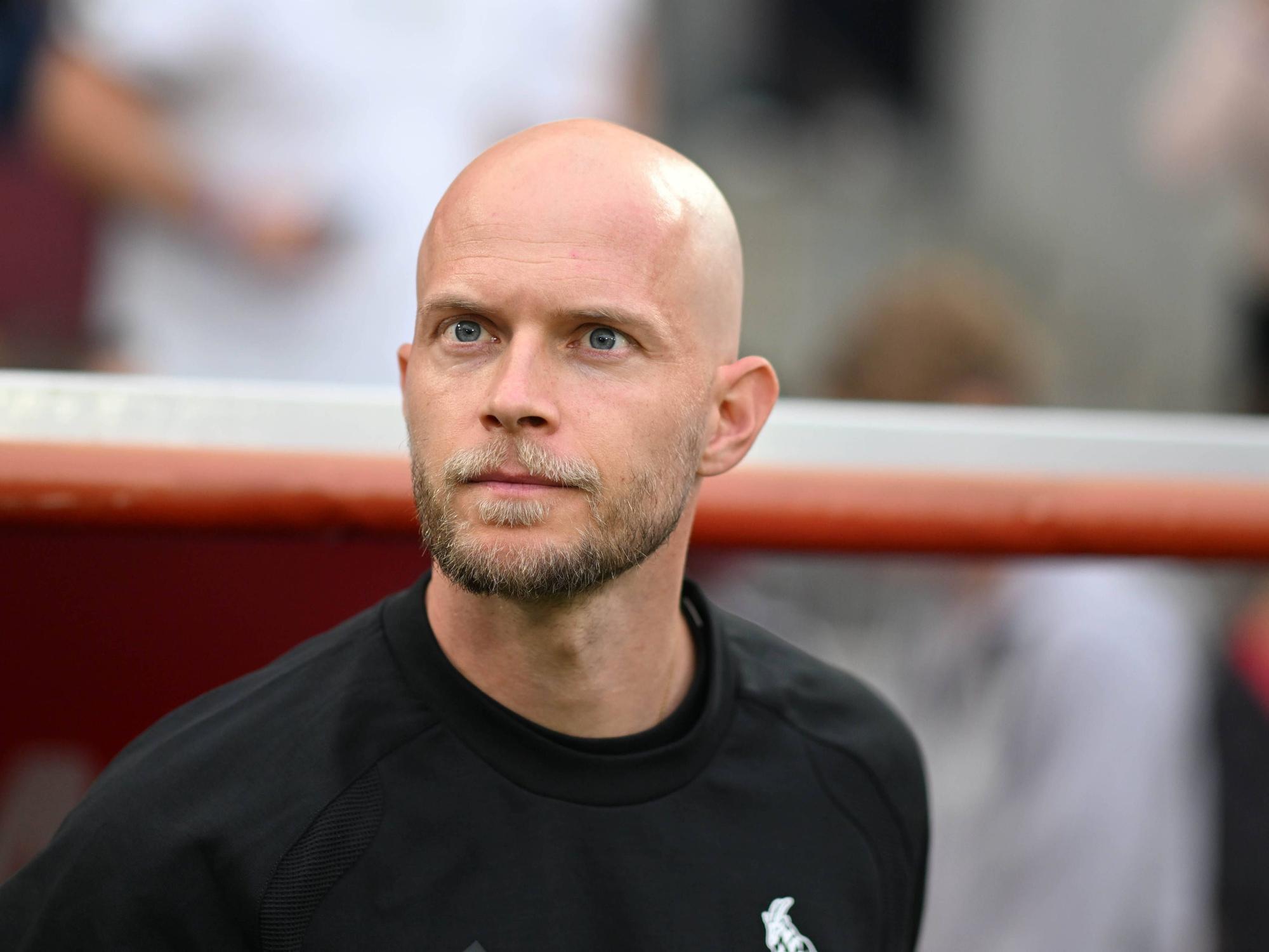 René Wagner steht vor der Trainerbank und schaut Richtung Südtribüne.