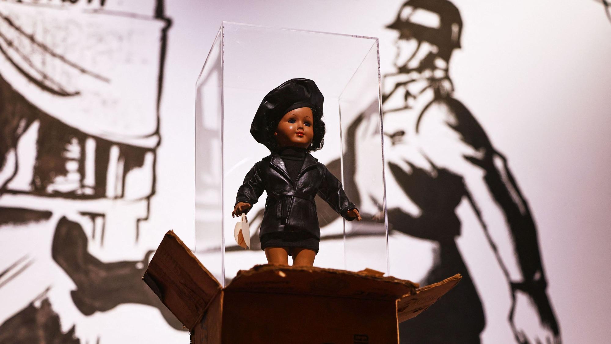 Die Puppe „Toxi“ von James Gregory Atkinson steht auf einem Care Paket in der Ausstellung «Along the Color Line - Spuren einer transatlantischen Moderne». Die Ausstellung ist vom 03.10.2026 bis zum 07.03.2027 im Museum Ludwig zu sehen.