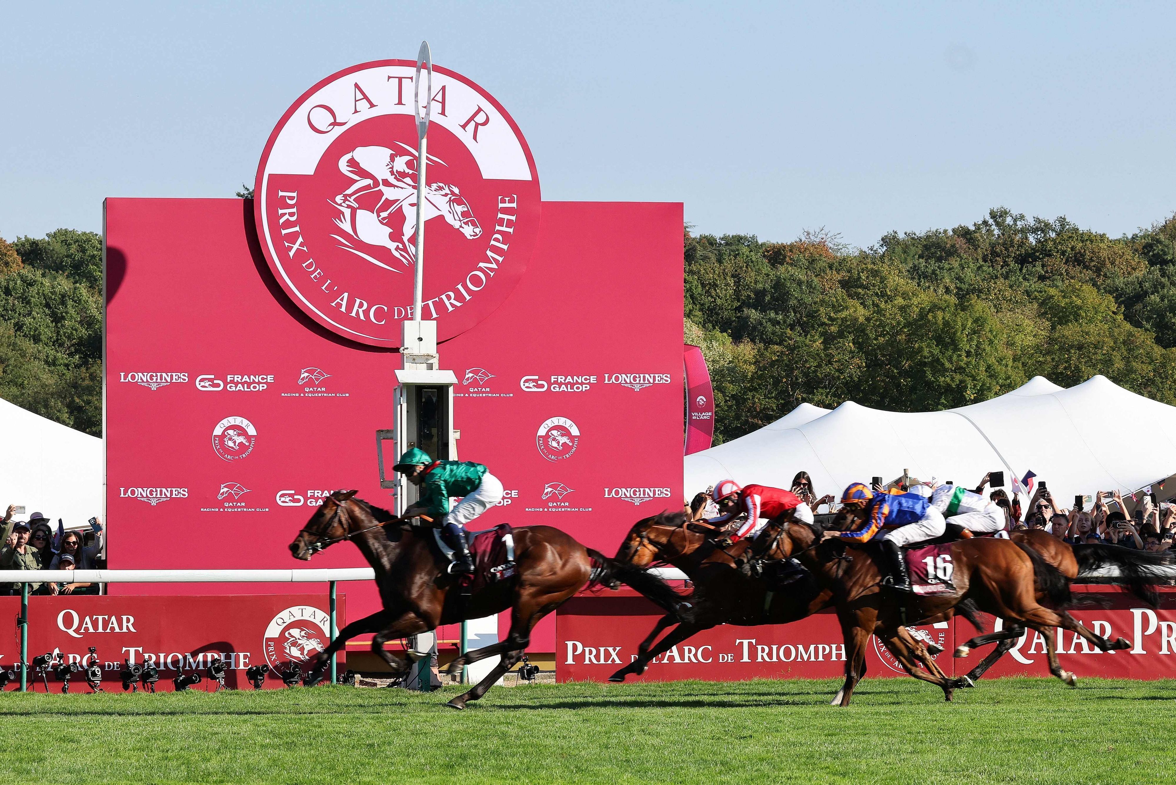 French jockey Mickael Barzalona riding Daryz (L) crosses the finish line to win the Qatar Prix de l'Arc de Triomphe horse race at the Longchamp race course, in Paris on October 4, 2026. (Photo by MEHDI FEDOUACH / AFP)