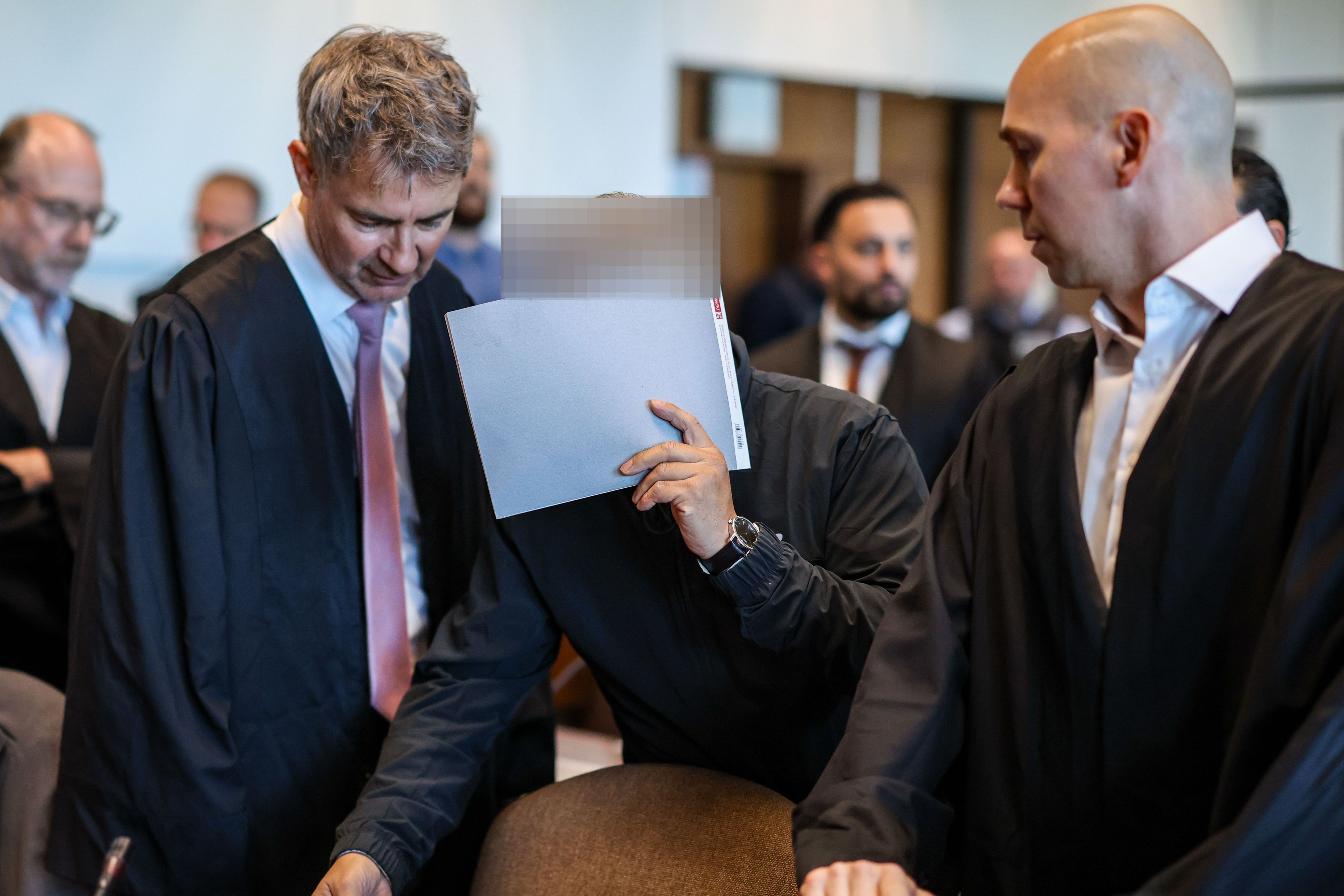 Einer der sieben Angeklagten mit den Verteidigern Marc Donay (l.) und Jonas Bau beim Prozessauftakt im Kölner Landgericht.