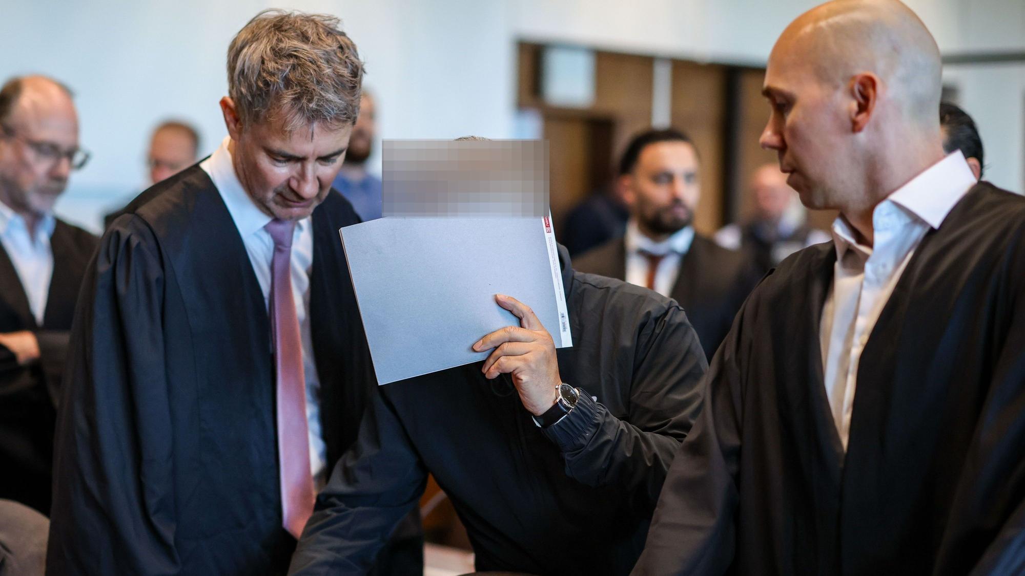 Einer der sieben Angeklagten mit den Verteidigern Marc Donay (l.) und Jonas Bau beim Prozessauftakt im Kölner Landgericht.