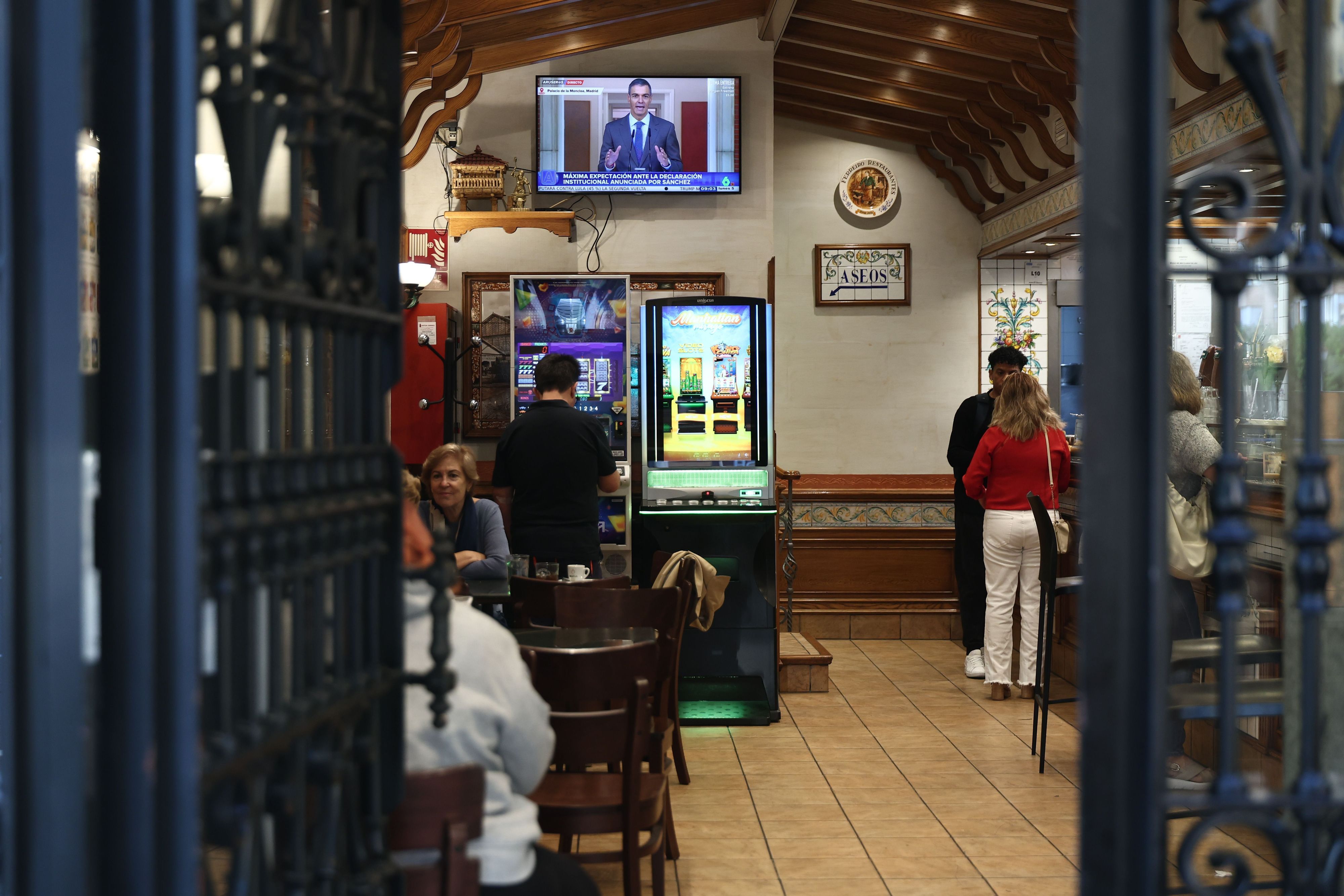 Mehrere Menschen verfolgen in Madrid (Spanien) in einer Bar die offizielle Erklärung des Ministerpräsidenten.