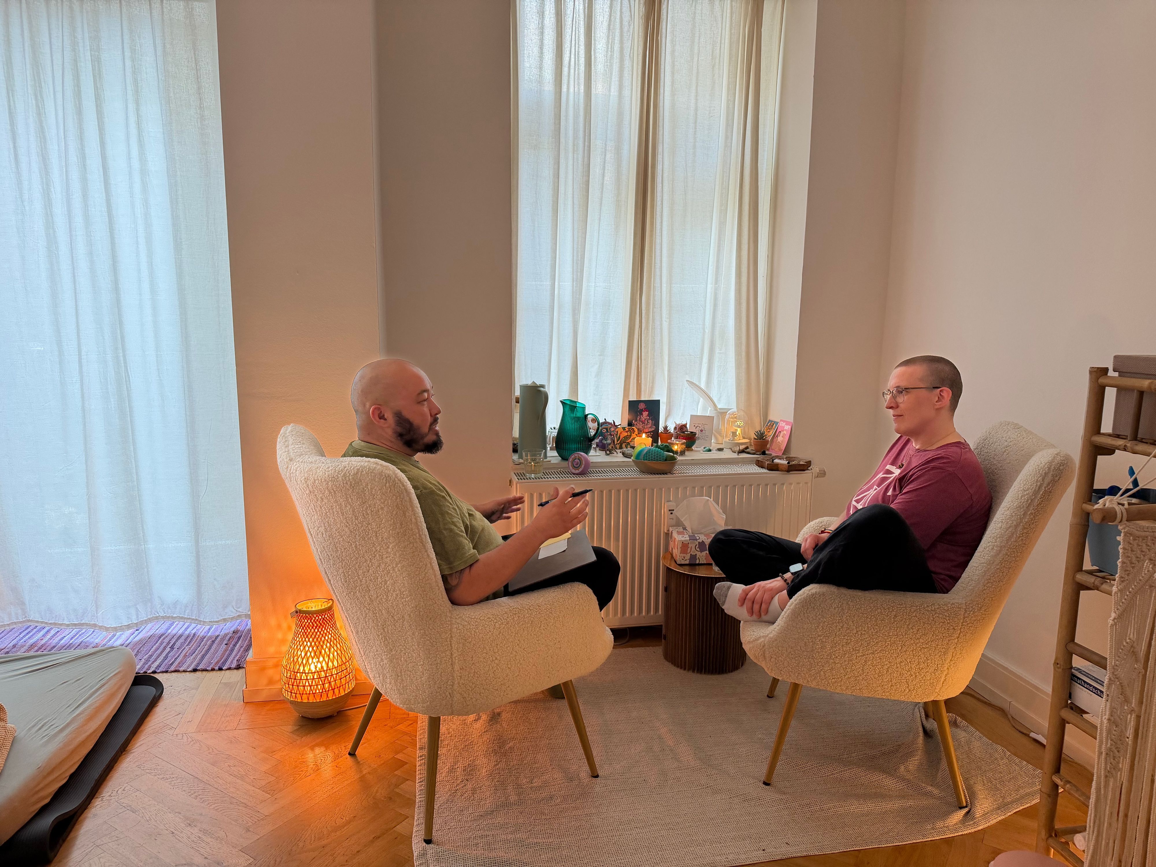 Zwei Menschen sitzen sich auf gemütlichen Stühlengegenüber.
