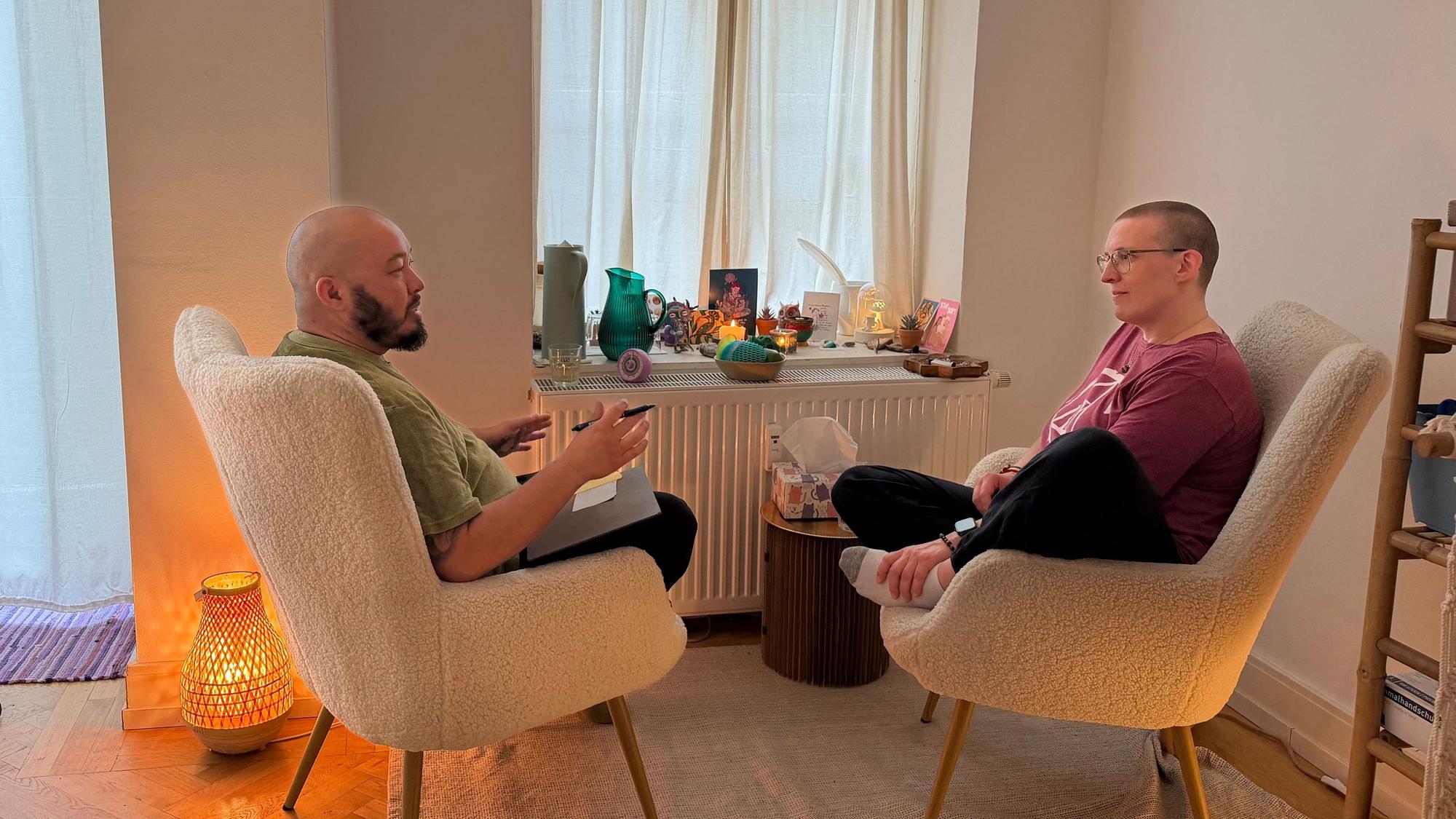 Zwei Menschen sitzen sich auf gemütlichen Stühlengegenüber.