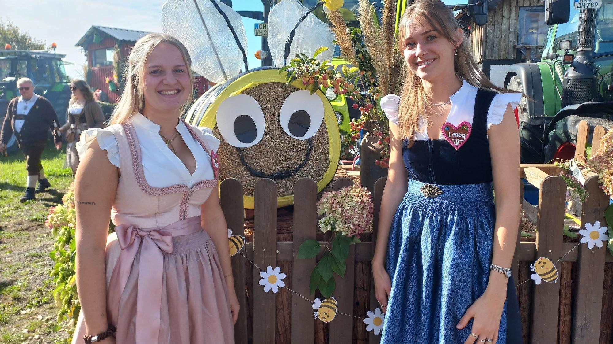 Zwei junge Frauen stehen vor einem Erntewagen.
