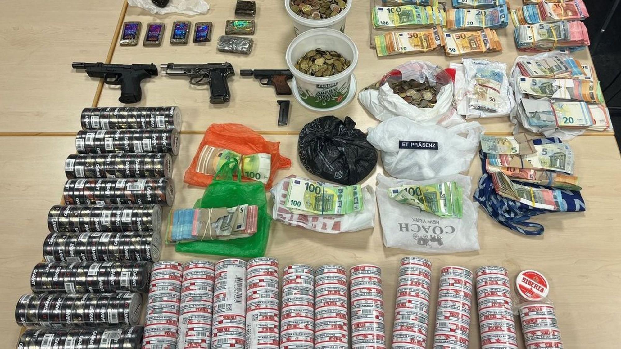 Sichergestellte Gegenstände wie Drogen, Waffen und Bargeld liegen auf einem Tisch.