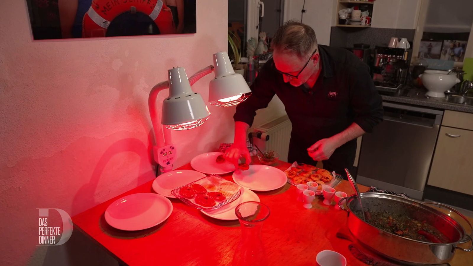 Beim wärmenden Rotlicht der Rheumalampe richtet Harry die Teller an.
 (Bild: RTL)