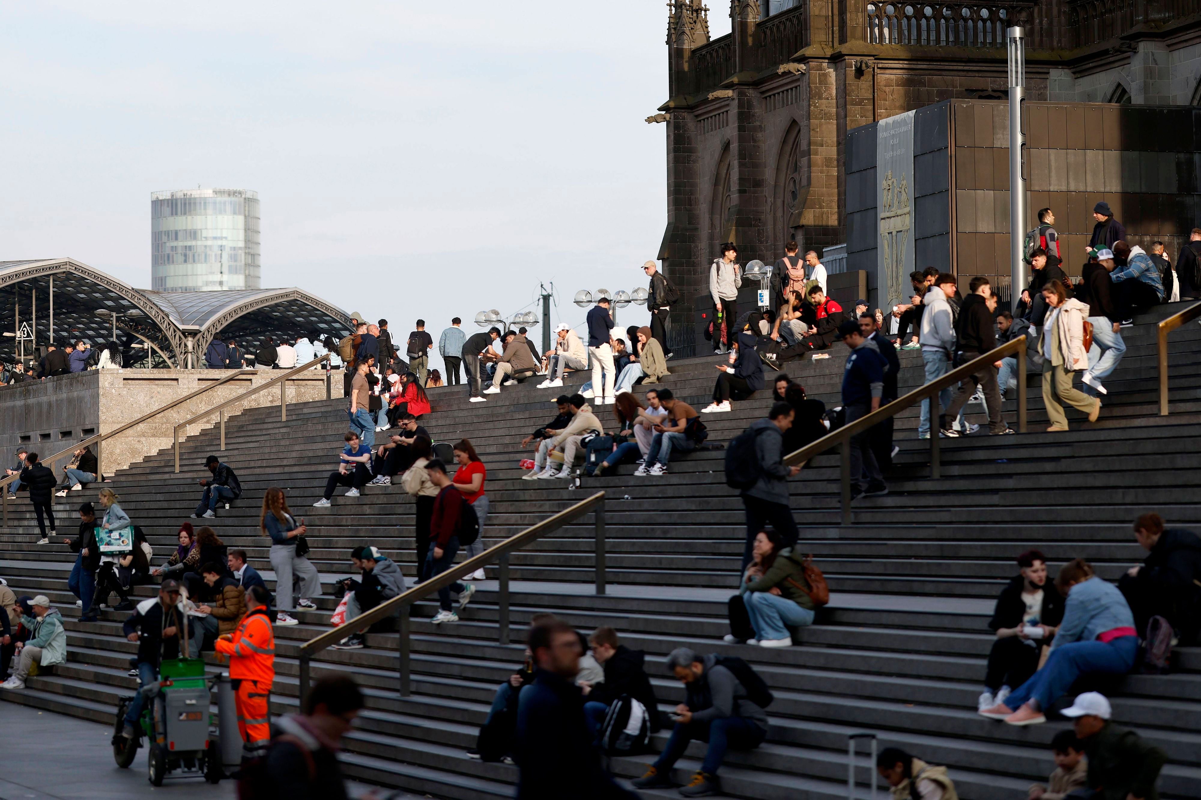 Menschen sitzen auf der Domtreppe am Kölner Dom.