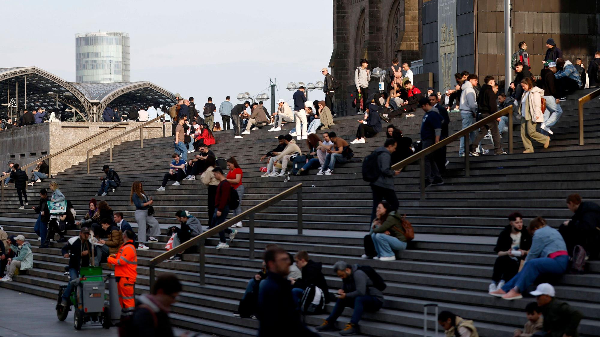 Menschen sitzen auf der Domtreppe am Kölner Dom.