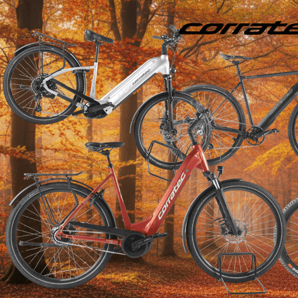 Corratec E-Bikes vor einem Hintergrund mit einer idyllischen Landstraße an einem strahlenden Sommernachmittag, ringherum viel Wiese und Wald. Zu sehen sind vier Fahrräder in den Farben Weiß, Rot und Dunkelgrau – darunter City- und Trekkingräder sowie ein Fully-Mountainbike. Oben die Logos von Rebike und Corratec, rechts oben ein blauer Button mit der Aufschrift „Bis -62% Rabatt zur UVP".