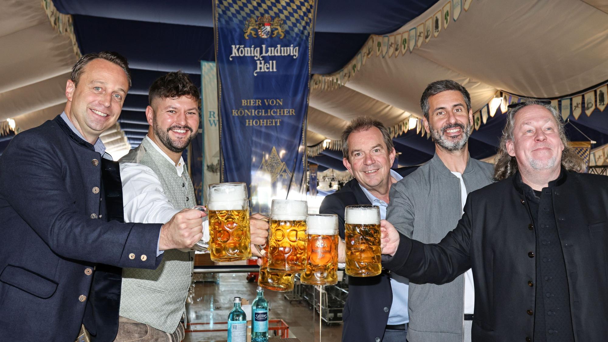 Männer prosten sich mit Bier zu.