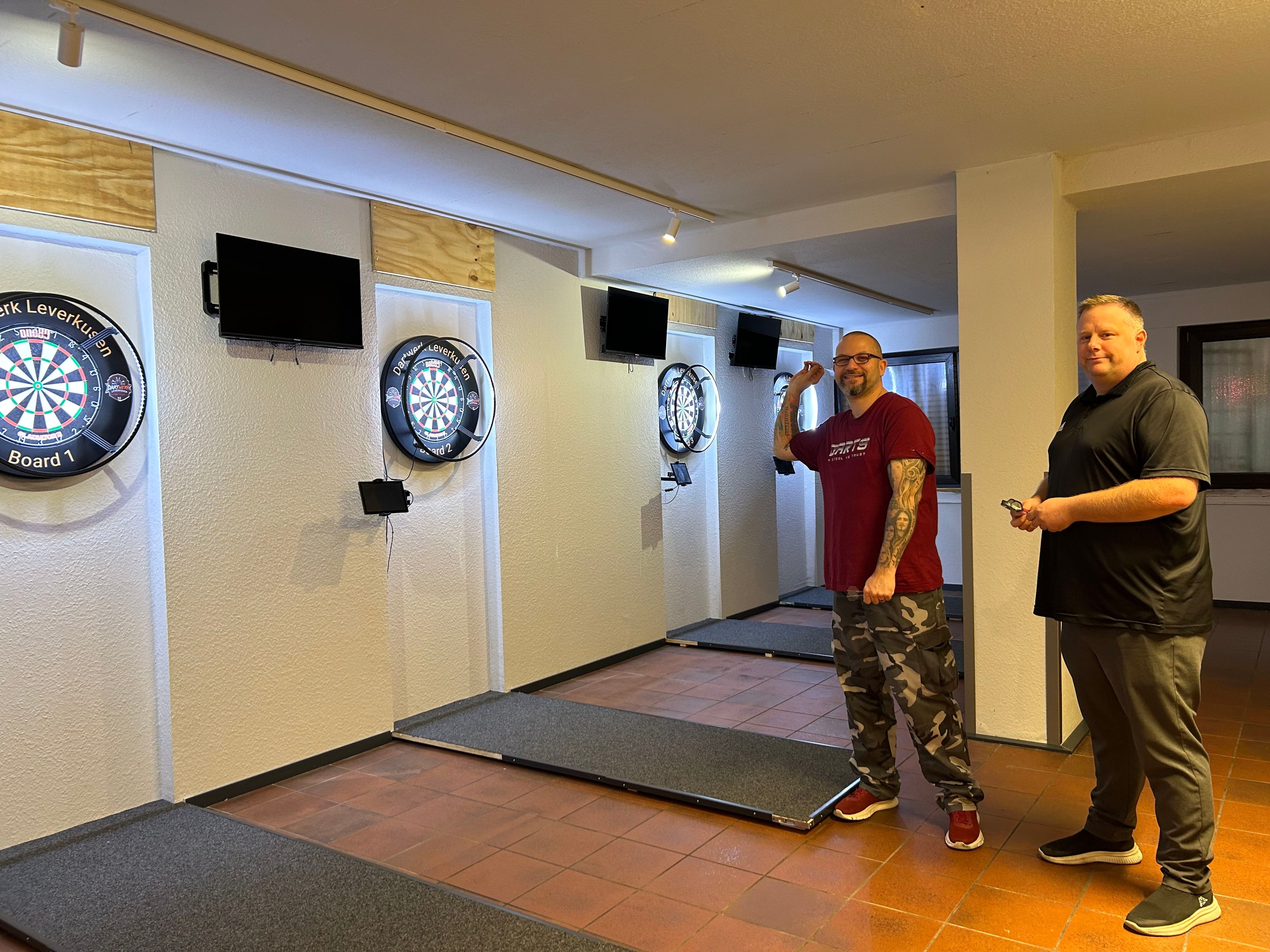Christian Claaßen und Johannes Grabarz beim Dartspielen. Die dekorativen Holzpaneele fehlen noch, trainiert wird bereits.