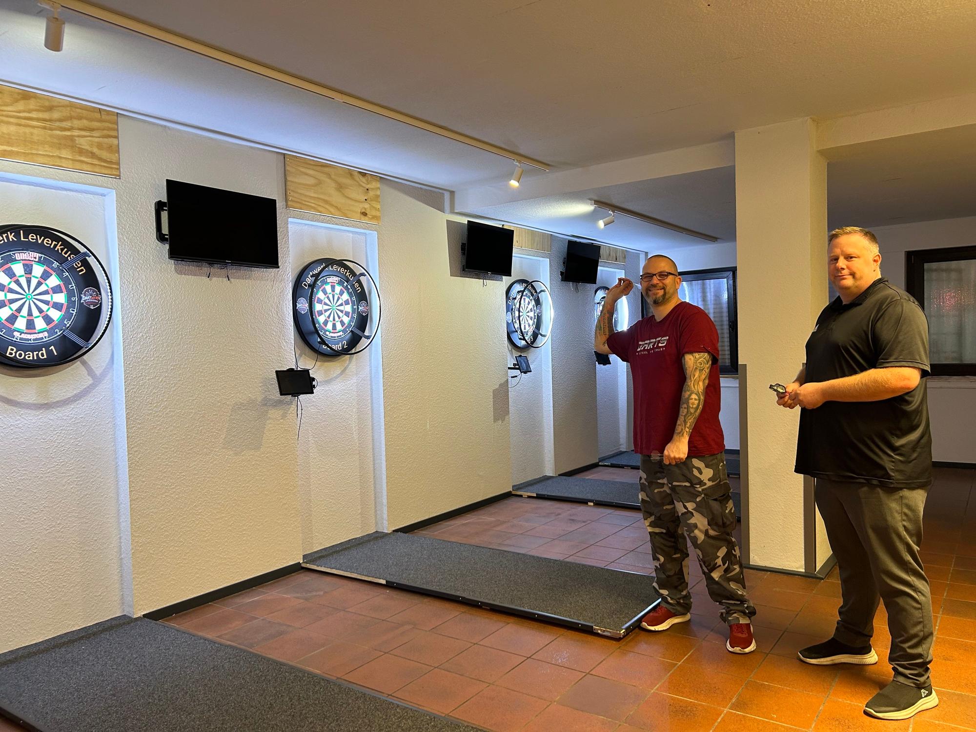 Christian Claaßen und Johannes Grabarz beim Dartspielen. Die dekorativen Holzpaneele fehlen noch, trainiert wird bereits.