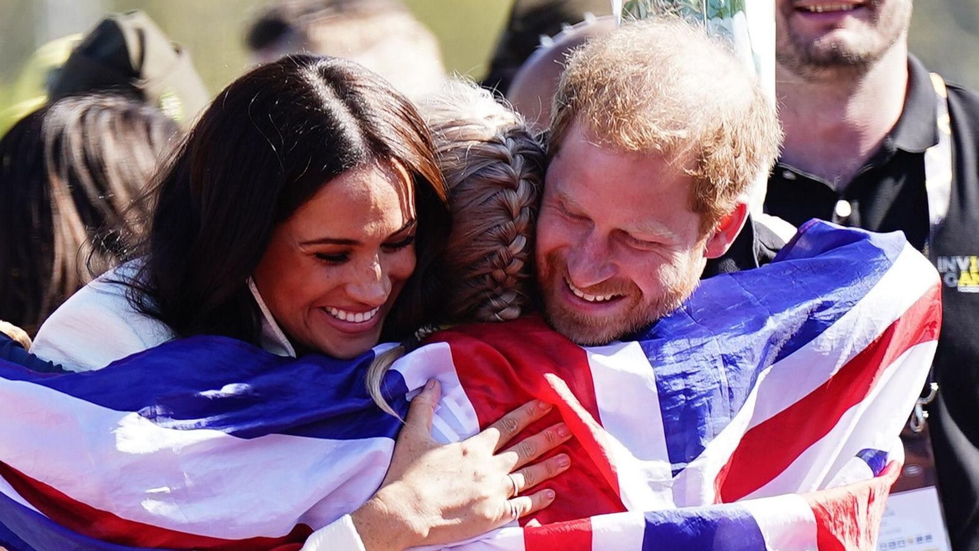 Prinz Harry (r), Herzog von Sussex, und Meghan (l), Herzogin von Sussex, umarmen die britische Teilnehmerin Lisa Johnston während der Leichtathletikwettbewerbe der Invictus Games 2022 im Zuiderpark.