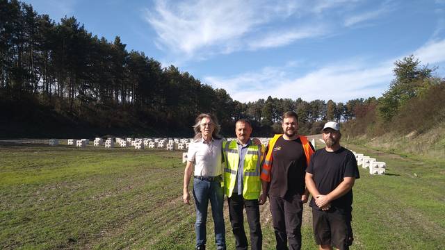 Vier Männer stehen auf einer großen Wiese, im Hintergrund sind PV-Elemente im Boden verankert.