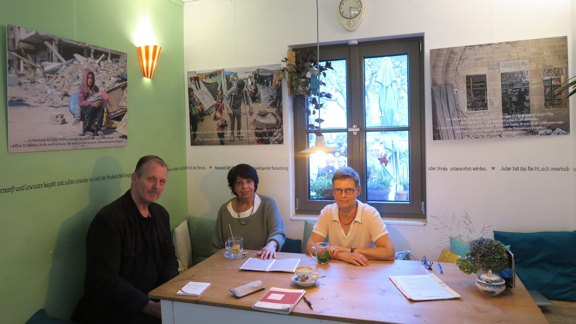 Ein Mann und zwei Frauen sitzen an einem Tisch in einem Café.