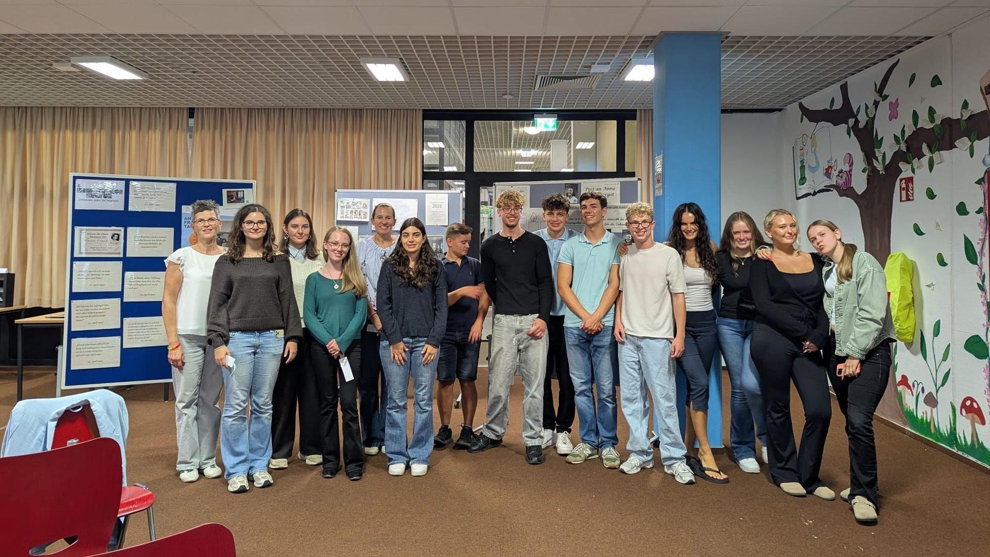 Eine Gruppe Schüler steht im Halbkreis in einem Raum vor Aufstelltafeln.