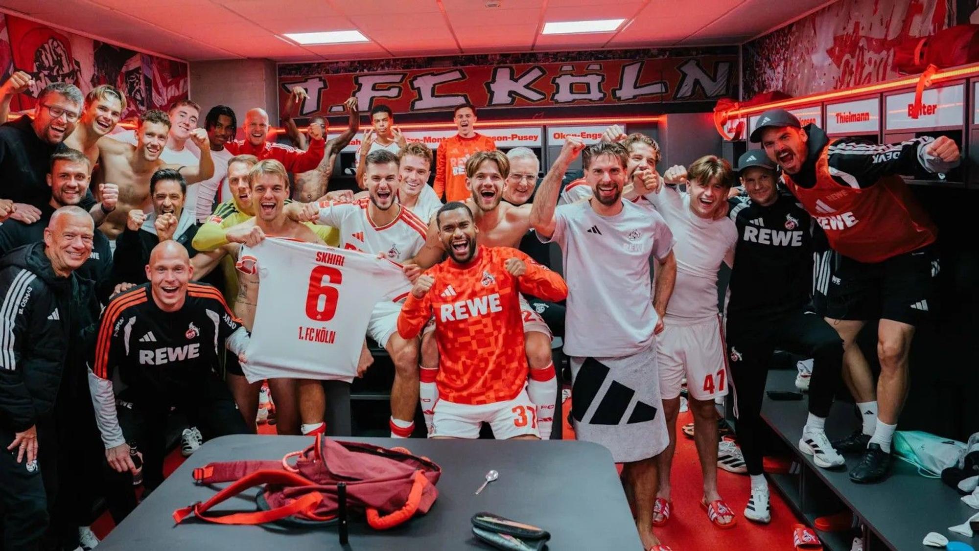 Die Kölner Derbysieger feiern in der Kabine mit dem Trikot ihres verletzten Teamkollegen Ellyes Skhiri.