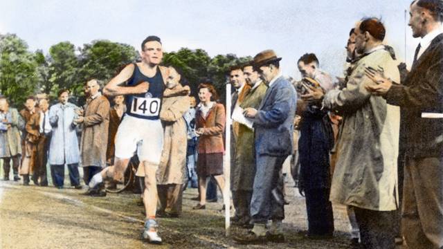 Alan Turing läuft an einer Reihe von Zuschauern vorbei..