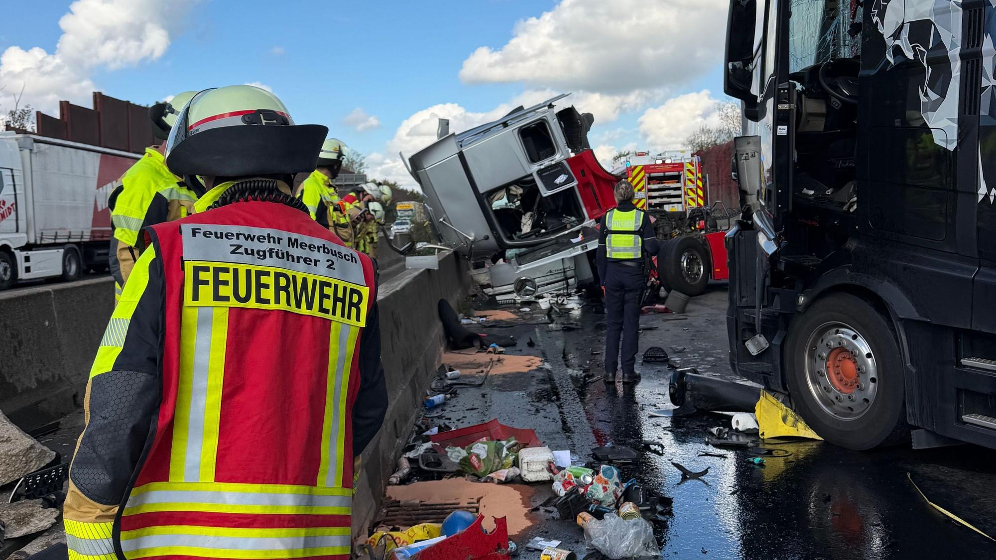 Einsatzkräfte sind bei einem Unfall auf einer Autobahn beschäftigt. Nach zwei Verkehrsunfällen ist die A57 in Richtung Niederlande auf unbestimmte Zeit voll gesperrt.