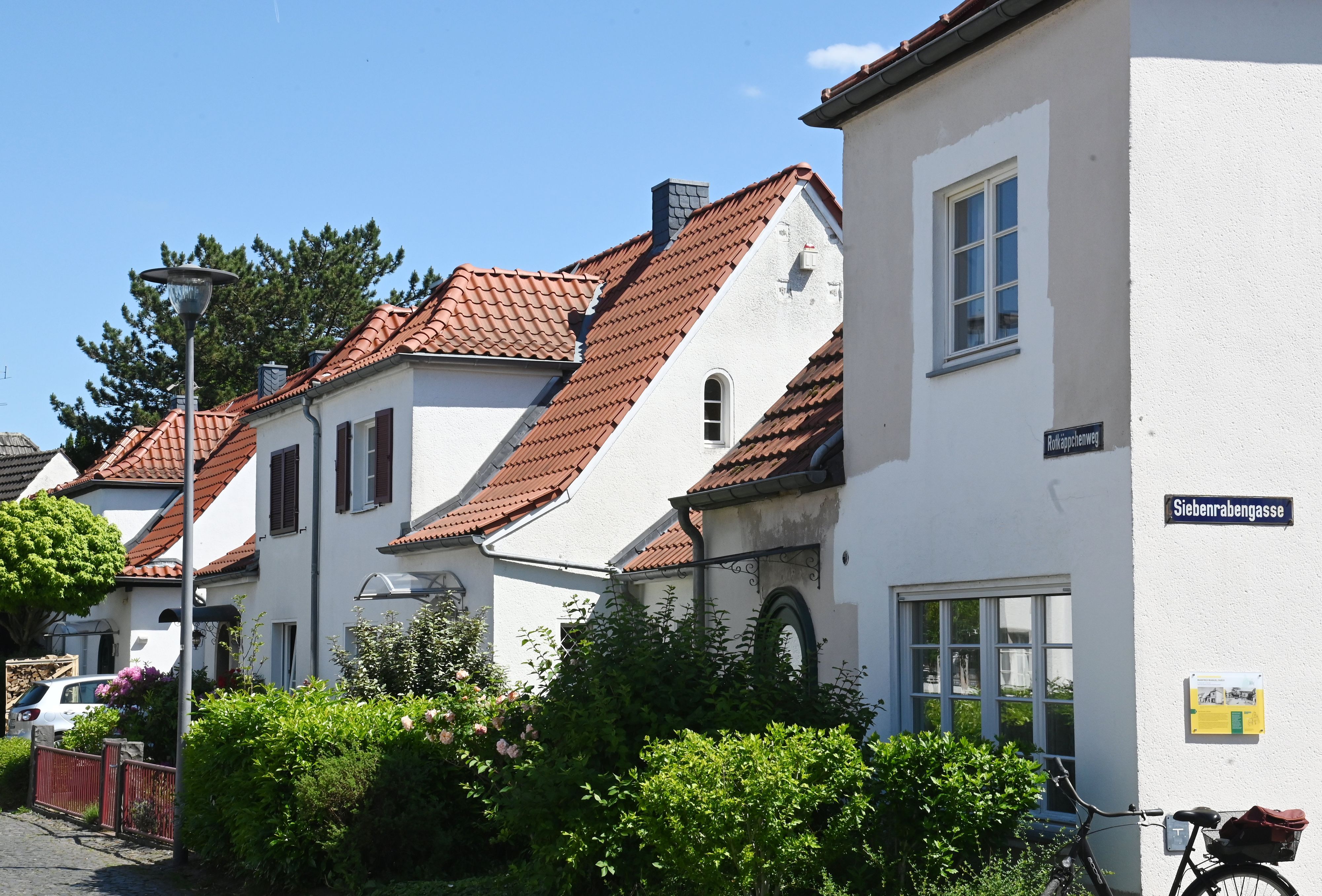 Hübsche weiße Häuser mit orangen Dachziegeln stehen an einer Straße.