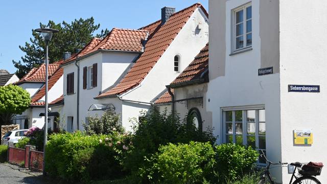 Hübsche weiße Häuser mit orangen Dachziegeln stehen an einer Straße.