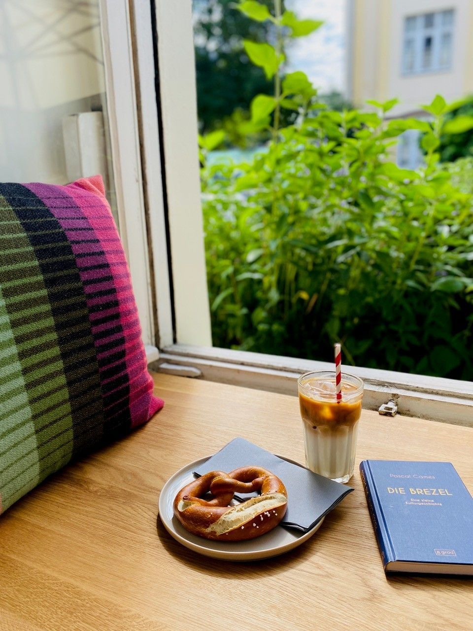 Laugenbrezel und Getränk stehen am offenen Fenster in einem Café in Sülz.