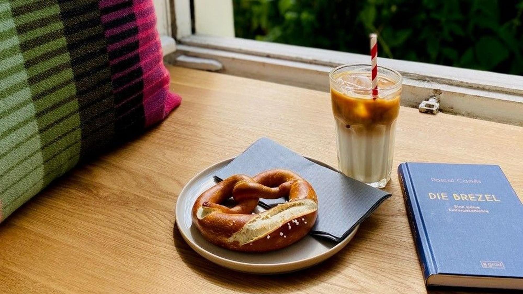 Laugenbrezel und Getränk stehen am offenen Fenster in einem Café in Sülz.