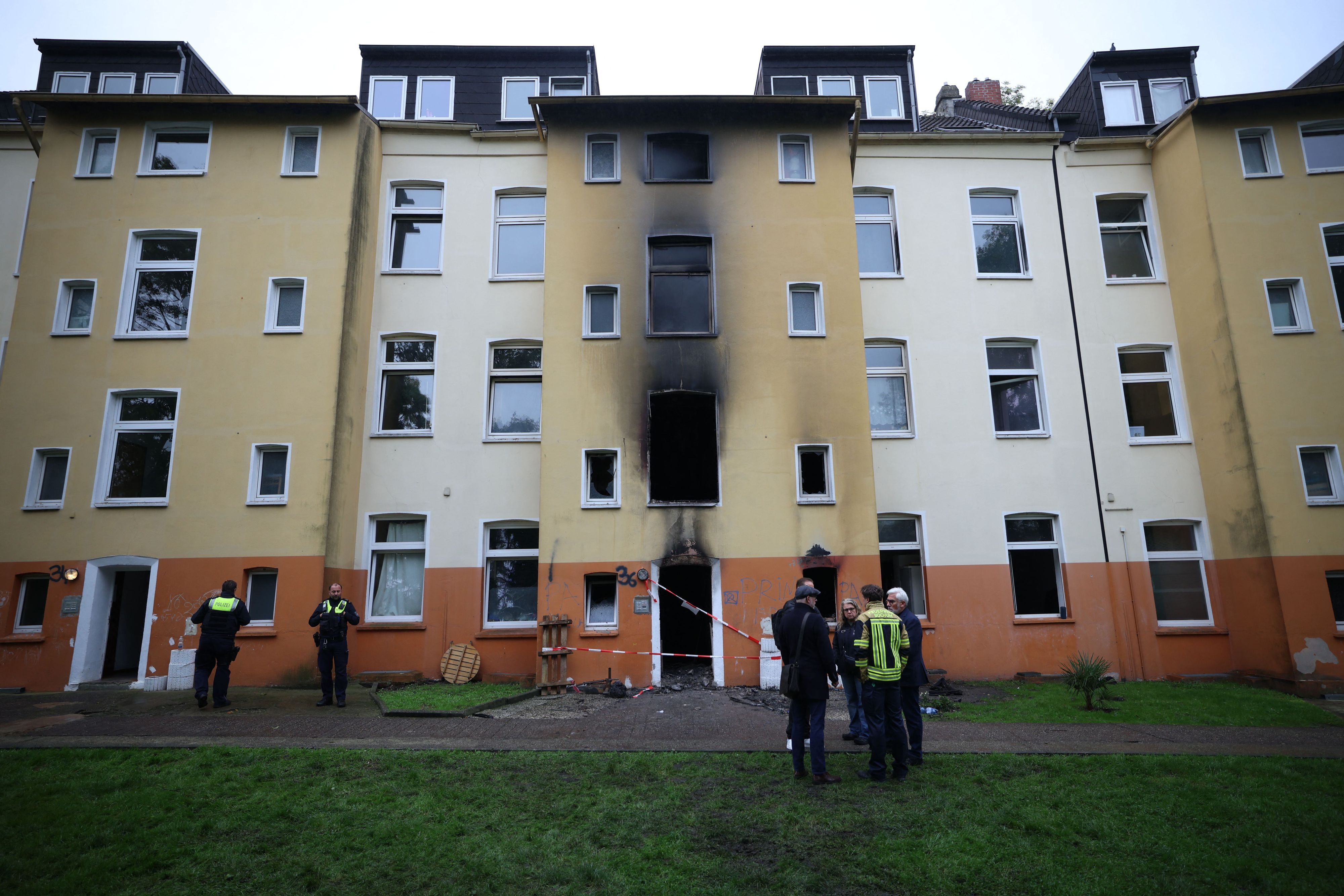 Feuerwehr, Polizei und Brandermittler stehen am Dienstag (13. Oktober) nach einem Brand vor einem  Mehrfamilienhaus im Stadtteil Hofstede.