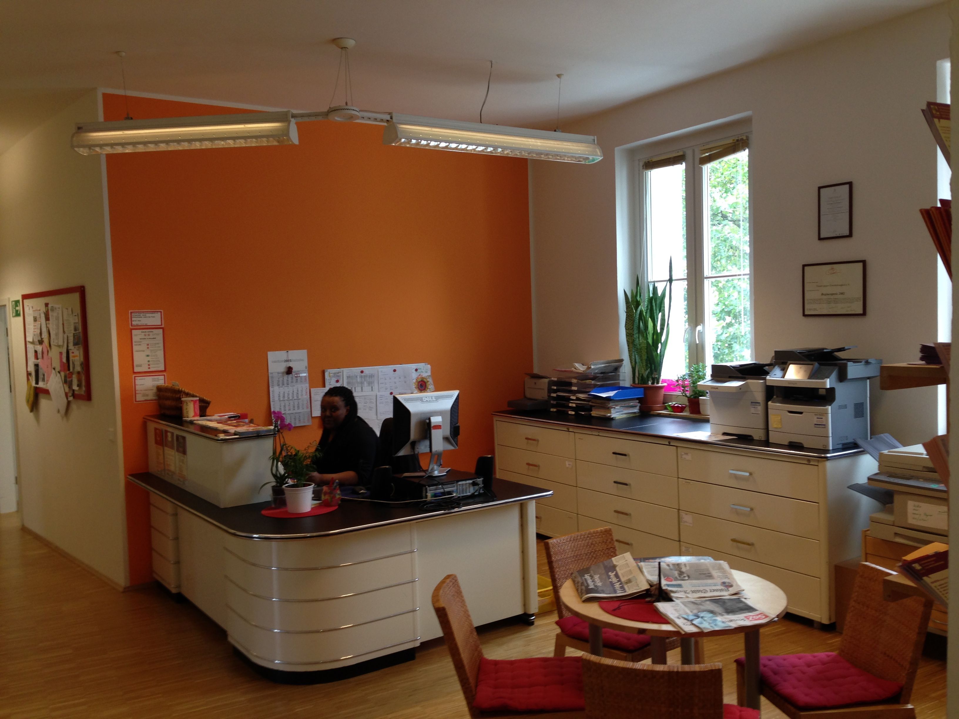 In einem großen Raum stehen Büromobiliar und ein runder Tisch mit drei Stühlen.