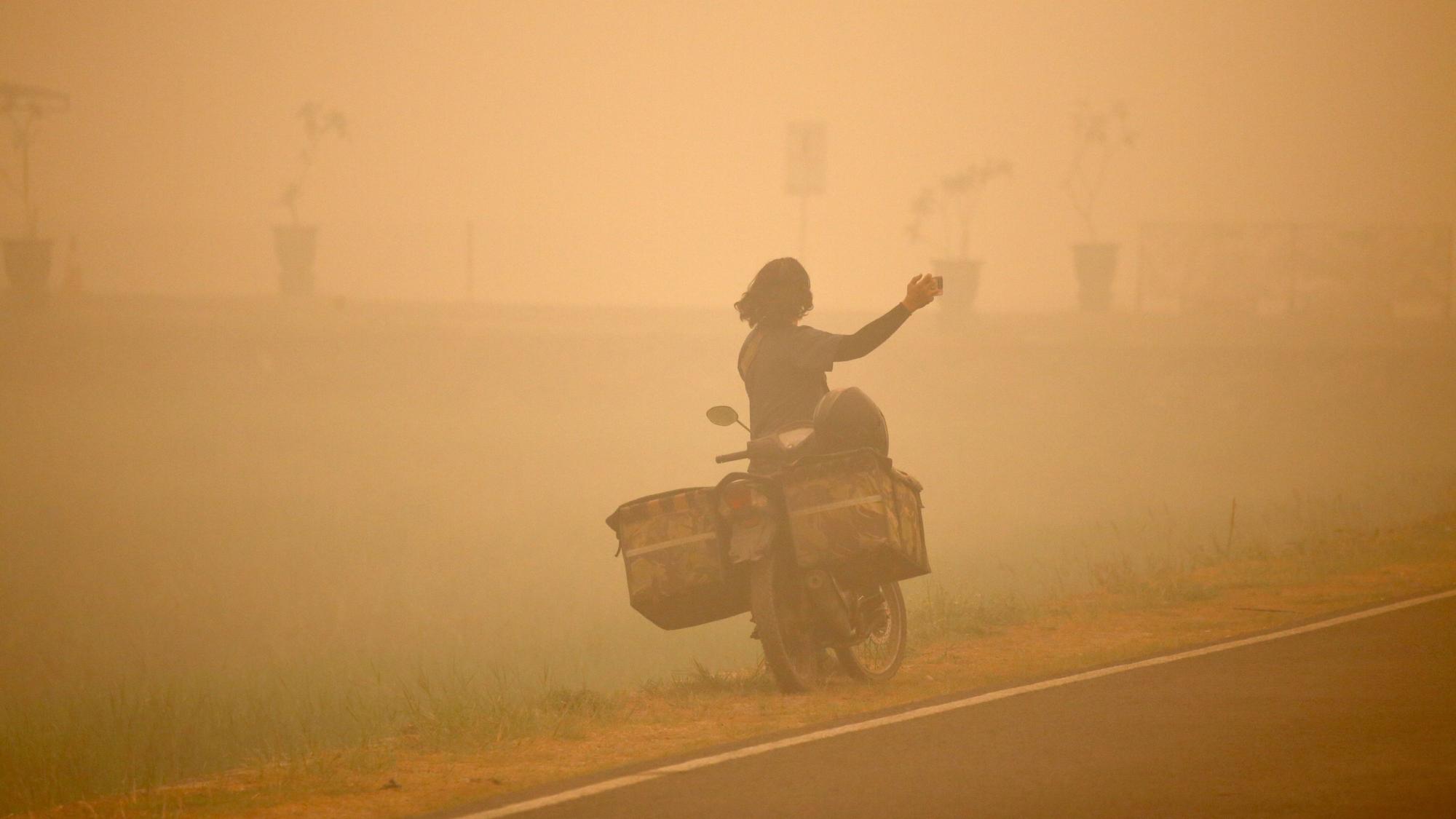 Eine Person macht Fotos inmitten des dichten Dunstes, der durch Wald- und Torfbrände in Palangka Raya, Zentralkalimantan, Indonesien, verursacht wird.