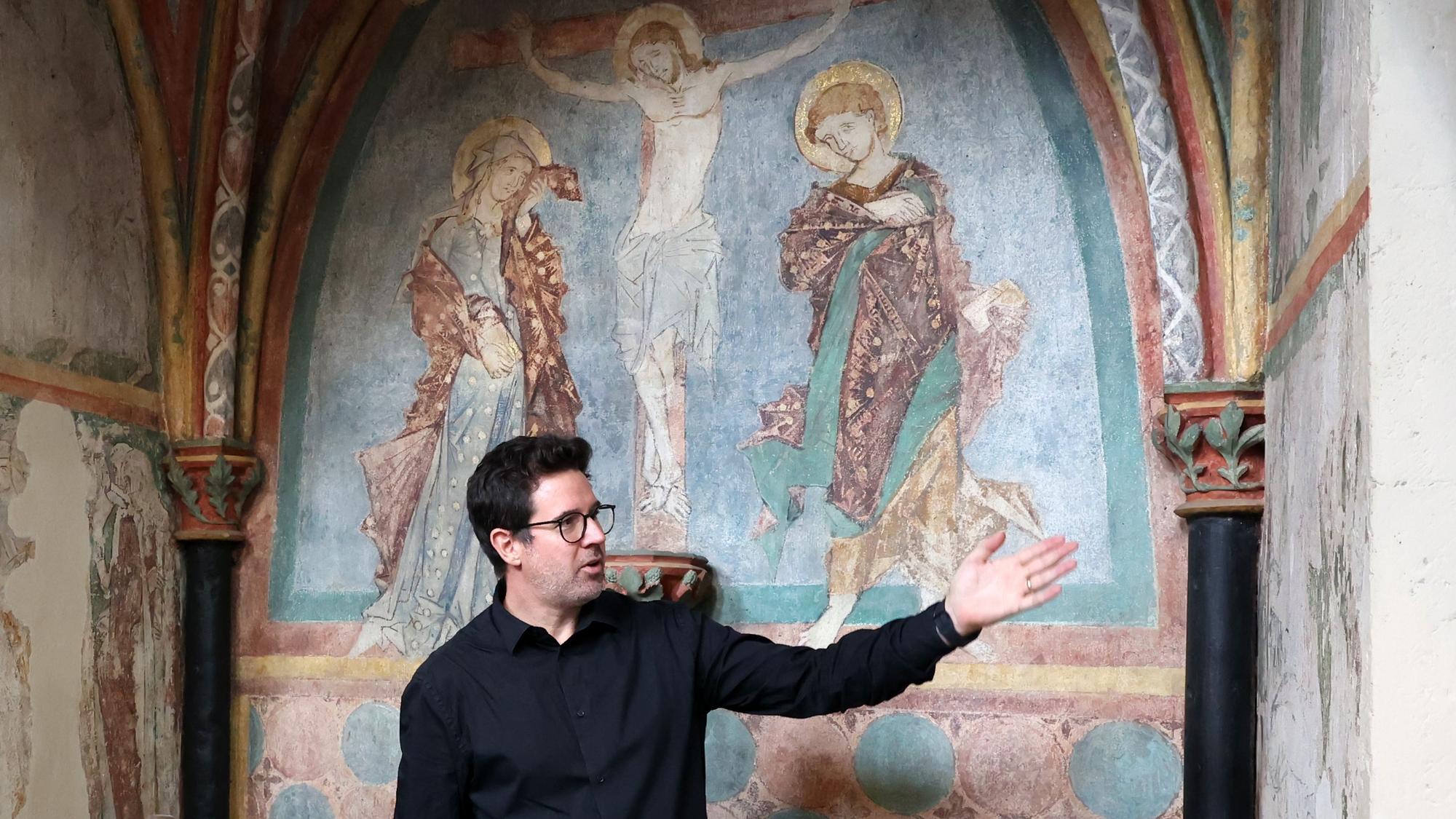 Kunsthistoriker Adam Stead vor den mittelalterlichen Wandmalereien in der Taufkapelle von St. Kunibert.