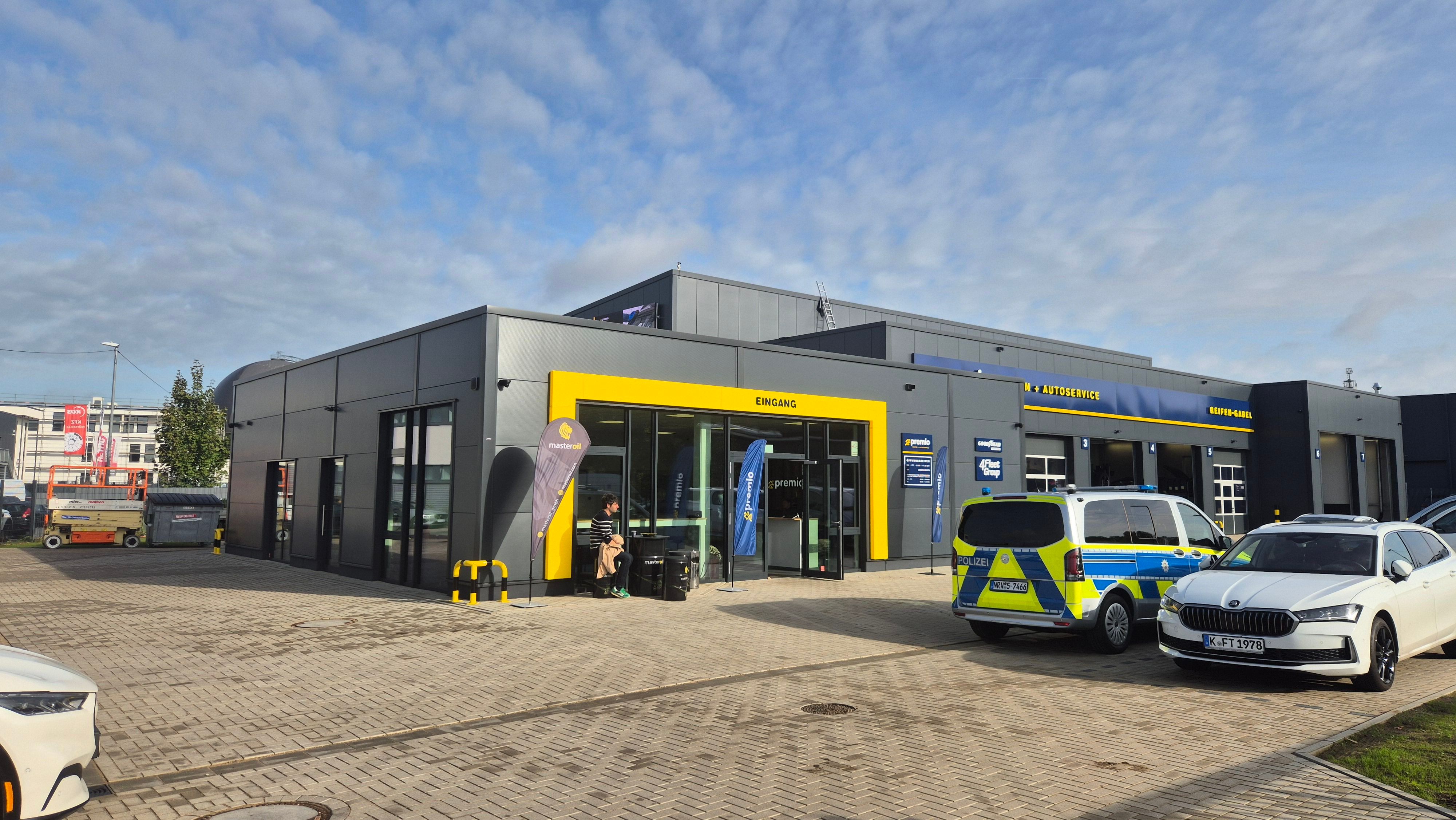 Eine Halle ist zu sehen, davor stehen Autos.