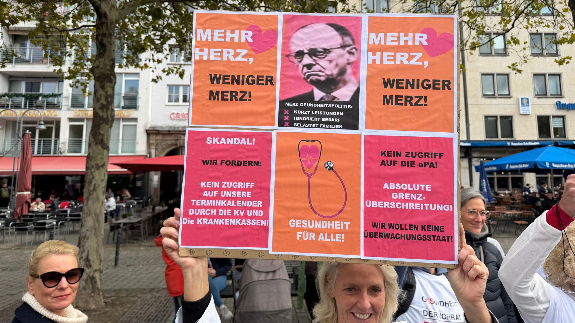 Demonstrierende in Köln machten mit dem Plakat „Mehr Herz, weniger Merz!“ und Forderungen gegen den Zugriff auf die elektronische Patientenakte (ePA) ihrem Ärger über die aktuelle Gesundheitspolitik Luft.