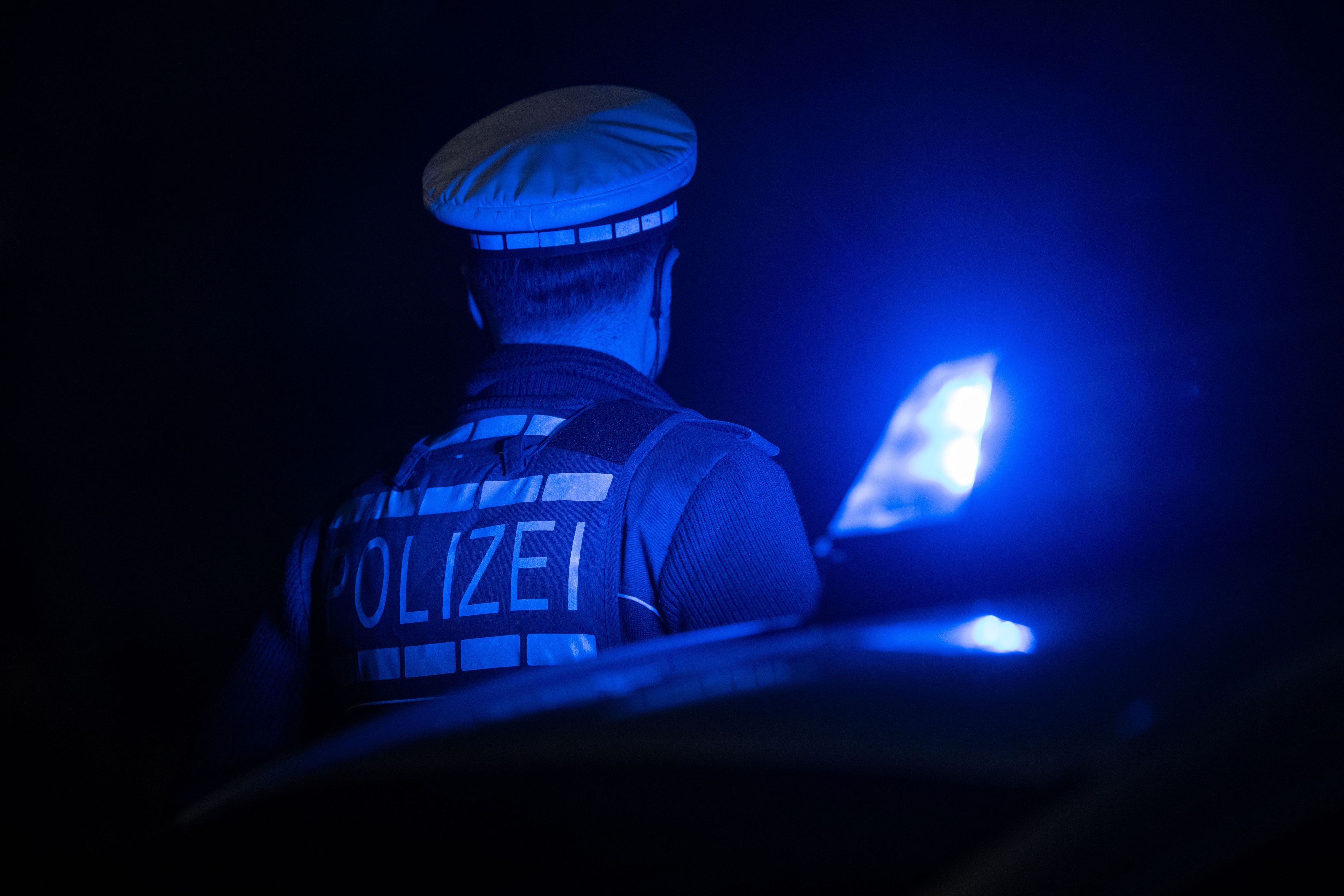 Ein Polizist steht im Blaulicht.
