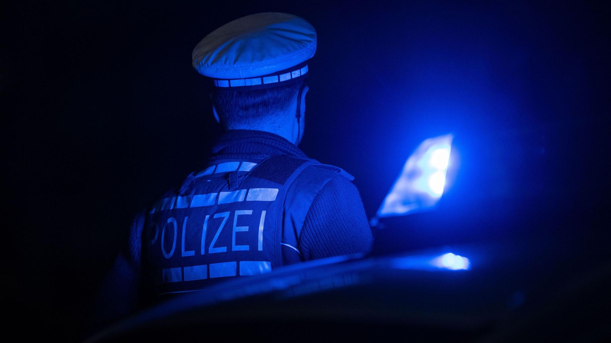 Ein Polizist steht im Blaulicht.