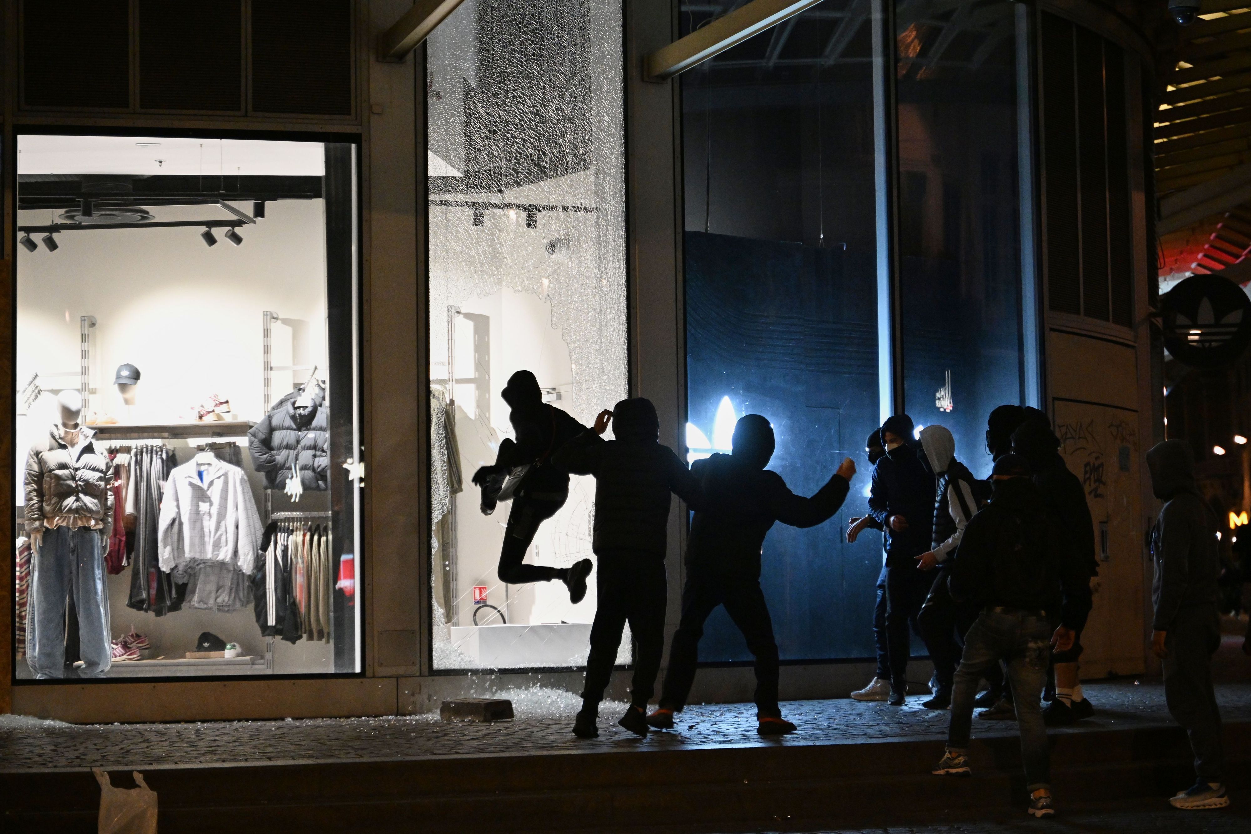Jugendliche zerschlagen bei Zusammenstößen zwischen Demonstranten und der Polizei in Paris eine Schaufensterscheibe.