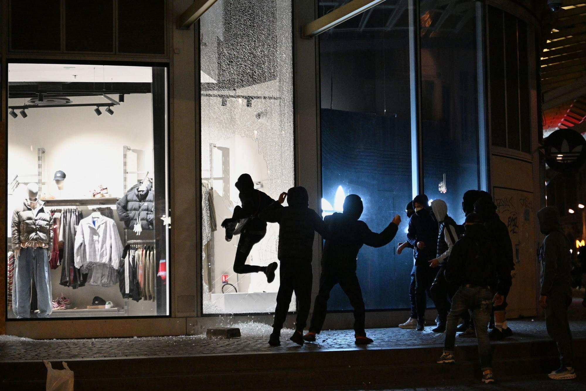 Jugendliche zerschlagen bei Zusammenstößen zwischen Demonstranten und der Polizei in Paris eine Schaufensterscheibe.