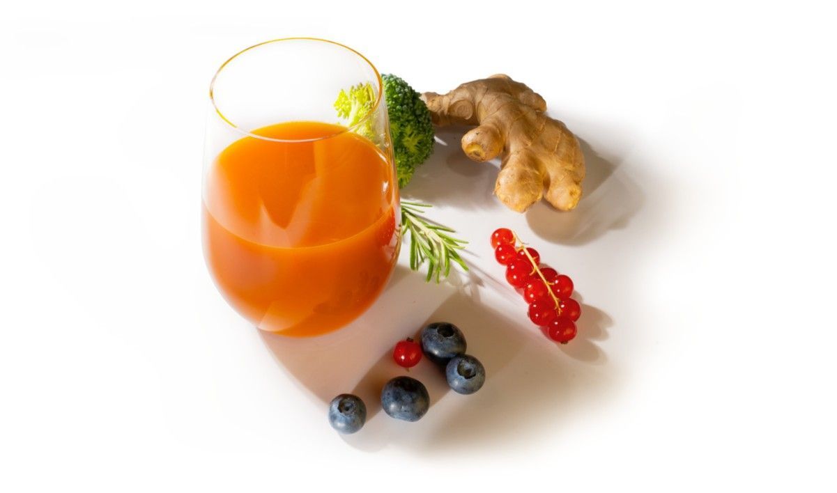 Glas mit verdünntem LaVita Mikronährstoffkonzentrat, daneben Brokkoli, Ingwer, Rosmarin, rote Johannisbeeren und Heidelbeeren