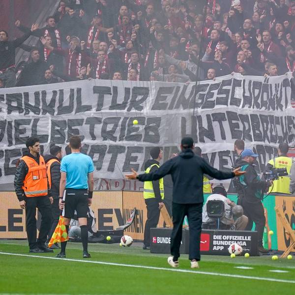 Spielunterbrechung in Leverkusen: SC-Freiburg-Trainer Julian Schuster steht mit ausgebreiteten Armen vor dem Gästeblock, nachdem Fans Tennisbälle auf das Spielfeld geworfen haben.